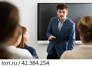 Positive skilled male coach explaining topic to group of people during foreign language class in auditory. Стоковое фото, фотограф Яков Филимонов / Фотобанк Лори