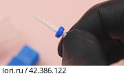 A specialist holds in his hands a ceramic cutter for hardware manicure with a blue distinctive washer on, another name for a cutter is a needle for processing nails. Стоковое видео, видеограф Сергей Чайко / Фотобанк Лори