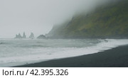 The black sand beach of Reynisfjara with waves hitting the shore on foggy rainy stormy day Vik, Iceland. Стоковое видео, видеограф Igor Tichonow / Фотобанк Лори