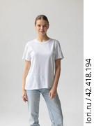 Beautiful blonde woman in a white T-shirt and blue jeans posing on a white background. Стоковое фото, фотограф Женя Канашкин / Фотобанк Лори