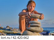 A girl on the beach is building a tower of stones. Стоковое фото, фотограф Светлана Семёновская / Фотобанк Лори