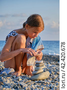 A girl on the beach is building a tower of stones. Стоковое фото, фотограф Светлана Семёновская / Фотобанк Лори