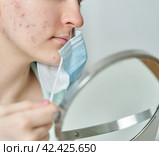 Faceless young female with problem skin wearing medical mask. Стоковое фото, фотограф Natalia Gdovskaia / Фотобанк Лори