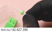 A specialist in black gloves holds in his hands a ceramic cutter for hardware manicure with a green distinctive washer, another name for a cutter is a needle for processing nails. Стоковое видео, видеограф Сергей Чайко / Фотобанк Лори