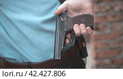 Young man dressed in a security guard uniform pulls out a gun, reload it and go ahead. Стоковое видео, видеограф EStarodubov / Фотобанк Лори