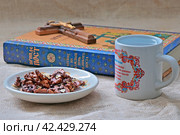 Великий пост. Ядра грецких орехов в блюдце и вода в кружке на фоне книги для ежедневного чтения и Распятия. (2023 год). Редакционное фото, фотограф Владимир Литвинов / Фотобанк Лори