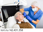 Cosmetologist making injections of botulotoxin in face of mature woman. Стоковое фото, фотограф Яков Филимонов / Фотобанк Лори