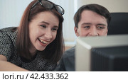 Two young office managers laughing and having fun looking at the computer monitor. Стоковое видео, видеограф EStarodubov / Фотобанк Лори
