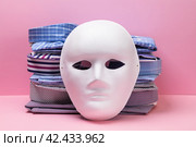 Stack of folded shirts and white mask on pink background, concept on clothing smuggling theme. Стоковое фото, фотограф Сергей Чайко / Фотобанк Лори