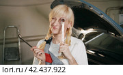 Автосервис. Portrait of an attractive woman in a mechanical uniform with a wrench in a car service. Стоковое видео, видеограф EStarodubov / Фотобанк Лори
