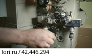Projectionist set in motion cine-film in an old 35 mm movie projector. Inclusion and start up of a movie projector. Стоковое видео, видеограф EStarodubov / Фотобанк Лори