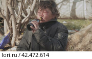 Бомж, бездомная женщина бродяга. Portrait homeless woman vagabond in a temporary place is drinking beer. Стоковое видео, видеограф EStarodubov / Фотобанк Лори