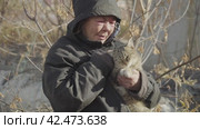 Бомж, бездомная женщина бродяга. Homeless woman vagabond in a temporary place caressing a wandering cat. Стоковое видео, видеограф EStarodubov / Фотобанк Лори