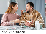 Man with cold symptoms sitting at home while girlfriend caring him. Стоковое фото, фотограф Яков Филимонов / Фотобанк Лори