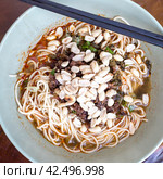 Close up view of plate with Sichuan style noodles like spicy noodle with chicken gizzard, minced, vegetables and peanut, Chinese cuisine (2018 год). Стоковое фото, фотограф VittoriaChe / Фотобанк Лори
