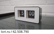 Перекидной циферблат часов будильника. Монтаж двух планов. Flip clock mechanism. 5:00 PM. Flip clock watch face. White brick wall in the background. Slow motion 240 fps. Стоковое видео, видеограф EStarodubov / Фотобанк Лори
