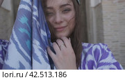 A young woman with long hair in an oriental robe and a skullcap walks through an ancient oriental city. Стоковое видео, видеограф Aleksey Kidisyuk / Фотобанк Лори