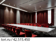 Conference room with red chairs, interior lighting, and empty white insulated screen. Business meetings, conferences, trainings, used as template for elegant design. Interior of the conference hall. Стоковое AI-изображение, AI-художник Aleksandr Golubev / Фотобанк Лори