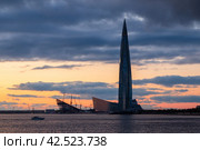 Санкт-Петербург, Россия. Вечерний пейзаж с огромным небоскребом на фоне закатного неба. Самое высокое здание в Европе. Современная архитектура и достопримечательности Санкт-Петербурга. (2019 год). Редакционное фото, фотограф Андрей Степанов / Фотобанк Лори