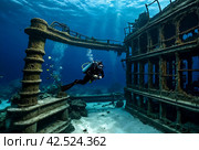 Scuba divers explore sunken ships at the bottom of the sea. Marine life underwater in blue ocean. Observation animal world. Scuba diving adventure in Red sea, coast Africa. Стоковое AI-изображение, AI-художник Aleksandr Golubev / Фотобанк Лори