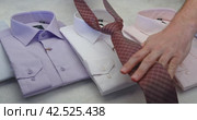 A man selects a tie to his shirt, applies it to each, and chooses a white shirt. Стоковое видео, видеограф Сергей Чайко / Фотобанк Лори