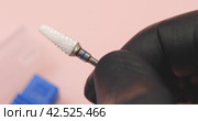 A specialist holds in his hands a cone-shaped ceramic cutter for hardware manicure with a blue notch for removing gel polish from nails. Стоковое видео, видеограф Сергей Чайко / Фотобанк Лори