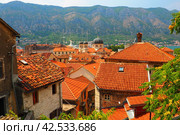 Kotor is a coastal city in Montenegro. Bay of Kotor. Red tiled roofs, mountain and chimneys of a tourist ship. Excursions and tourism. Cathedral of Saint Tryphon. Medieval old towns in the Adriatic (2022 год). Стоковое фото, фотограф Юлия Петровская / Фотобанк Лори