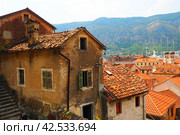 Kotor is a coastal city in Montenegro. Bay of Kotor. Red tiled roofs, mountain and chimneys of a tourist ship. Excursions and tourism. Cathedral of Saint Tryphon. Medieval old towns in the Adriatic (2022 год). Стоковое фото, фотограф Юлия Петровская / Фотобанк Лори