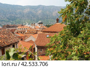 Kotor is a coastal city in Montenegro. Bay of Kotor. Red tiled roofs, mountain and chimneys of a tourist ship. Excursions and tourism. Cathedral of Saint Tryphon. Medieval old towns in the Adriatic (2022 год). Стоковое фото, фотограф Юлия Петровская / Фотобанк Лори