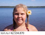 В жаркий летний день ребенок отдыхает на озере. Девочка на пляже. Девочка с белой водяной лилией. Водяная лилия, кувшинка, нимфея - растение семейства кувшинковых. On a hot summer day, a child is relaxing on the lake. A girl on the beach. A girl with a white water lily. Water lily, water lily, nymphaea is a plant of the water lily family. Стоковое фото, фотограф Мария / Фотобанк Лори