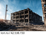 Remains of destroyed industrial building with internal communications. Demolition of building on territory plant. Background with dilapidated building and fragments of bricks and construction debris. Стоковое AI-изображение, AI-художник Aleksandr Golubev / Фотобанк Лори