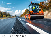 Road Construction Site with Steamroller Compacting Asphalt Pavement and Fresh White Lane Markings. Стоковое AI-изображение, AI-художник Юрий Поздников / Фотобанк Лори