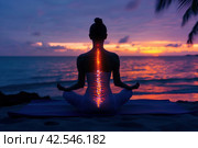 Woman Meditating on Beach at Sunset with Spine Enlightened by Setting Sun. Стоковое AI-изображение, AI-художник Юрий Поздников / Фотобанк Лори