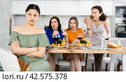 Offended Asian woman listening to disapproval of friends at house party. Стоковое фото, фотограф Яков Филимонов / Фотобанк Лори