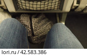 Women's legs in denim pants in a narrow gap between seats on an airplane. Economy class for air travel. A woman moves her legs to avoid blood clots and varicose veins. Travel, flights and business. Стоковое видео, видеограф Юлия Петровская / Фотобанк Лори