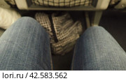 Women's legs in denim pants in a narrow gap between seats on an airplane. Economy class for air travel. A woman moves her legs to avoid blood clots and varicose veins. Travel, flights and business. Стоковое видео, видеограф Юлия Петровская / Фотобанк Лори