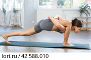 Young attractive smiling woman practicing side crow pose variation parsva bacasana yoga on mat in yoga studio. Стоковое фото, фотограф Яков Филимонов / Фотобанк Лори