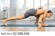 Young attractive smiling woman practicing side crow pose variation parsva bacasana yoga on mat in yoga studio. Стоковое фото, фотограф Яков Филимонов / Фотобанк Лори
