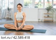 Cheerful young woman performing Baddha Konasana in studio. Стоковое фото, фотограф Яков Филимонов / Фотобанк Лори