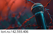 Studio microphone for recording on a gloomy background with barbed wire. The concept of freedom of speech. Стоковое AI-изображение, AI-художник Ярославский Максим / Фотобанк Лори