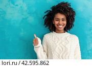 ctp afroamerican young woman in white sweater with thumbs up while pointing to right. Стоковое AI-изображение, AI-художник Юлия Гапеенко / Фотобанк Лори