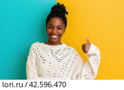 ctp afroamerican young woman in white sweater with thumbs up while pointing to right. Стоковое AI-изображение, AI-художник Юлия Гапеенко / Фотобанк Лори