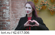 Mime young woman in a black coat making heart shape out of the hands and then blowing a kiss. Happy Valentines Day. Руками знак сердце и воздушный поцелуй. Стоковое видео, видеограф EStarodubov / Фотобанк Лори