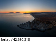 Вечерний морской пейзаж. Вид с воздуха на скалистый мыс и морской залив на закате. Заходящее солнце над побережьем. Вечерние сумерки. Путешествие на Дальний Восток России. Мыс Нюкля, Охотское море, Магаданская область, Россия. Стоковое фото, фотограф Андрей Степанов / Фотобанк Лори