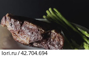 Smoked lamb ribs and ripe rye pods rotate on a white plate on a dark background. Close-up shooting. Стоковое видео, видеограф Ярославский Максим / Фотобанк Лори