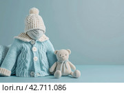 Stack of baby knitted clothes and teddy bear toy on table. Set of newborn child rompers, hat and jumper. Fashion infant accessories isolated pastel blue background, empty space. Kid's toys and clothes. Стоковое AI-изображение, AI-художник Марина Демидюк / Фотобанк Лори