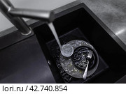 Kitchen sink with dishes and water running. Стоковое фото, фотограф Viktor Cap / PantherMedia / Фотобанк Лори