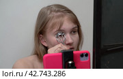 Woman is curling eyelashes using an eyelash curler. Brings the curler to eye, closes the clamp around lashes, holds it for a short time (2024 год). Редакционное видео, видеограф А. А. Пирагис / Фотобанк Лори
