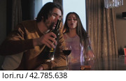 An alcoholic drinks red wine and has a disagreement with his girlfriend. Стоковое видео, видеограф Strunov David / Фотобанк Лори