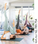 Women performing Eka Pada Sarvangasana with one leg bent at yoga training. Стоковое фото, фотограф Яков Филимонов / Фотобанк Лори
